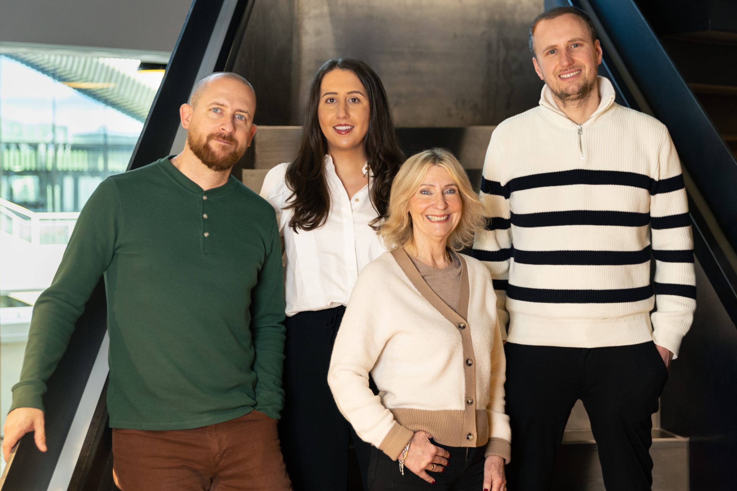 Four members of the Faze agency team stood on steps smiling at the camera, two men and two women of different ages